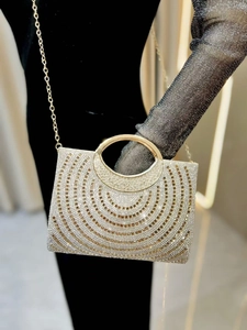 Macro view of crystal rhinestones and circular handle on the champagne evening clutch bag
