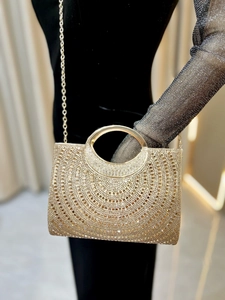 Close-up of golden clutch bag with sunburst crystal pattern and round metal handle