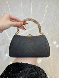 Detail of black glitter evening bag featuring a rhinestone-encrusted gold metal handle
