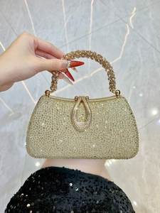 Macro detail of luxury gold evening clutch bag with shimmering rhinestones and ring handle