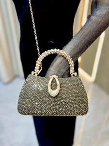 Macro view of luxurious black dinner clutch featuring golden rhinestones and diamond handle
