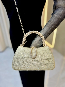 Close-up of luxury champagne gold evening bag with glittering rhinestones and metal chain