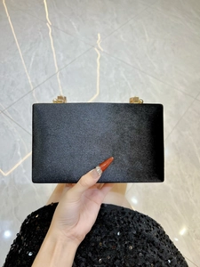 Détail d'une pochette en velours noir avec fermoirs cylindriques en métal doré