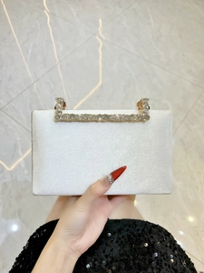 Détail d'une pochette de soirée en satin blanc avec poignée en strass et fermoir doré