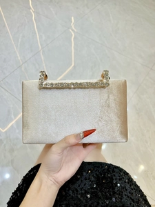 Détail de la pochette en satin champagne avec poignée ornée de strass étincelants