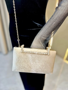 Détail d'une pochette de soirée en velours champagne avec poignée en strass et chaîne