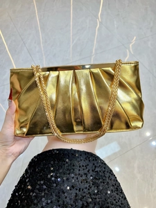 Detail of gold metallic pleated evening clutch bag with elegant chain shoulder strap