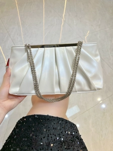 Detail view of white ruched evening clutch featuring pearl luster and silver chain strap