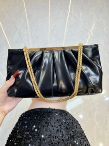 Detail of elegant black pleated evening clutch bag with double golden chain straps