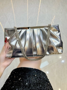 Detailed view of silver pleated evening clutch with metallic finish and fine chain strap