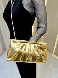 Detail of golden pleated evening clutch with metallic finish and delicate chain strap