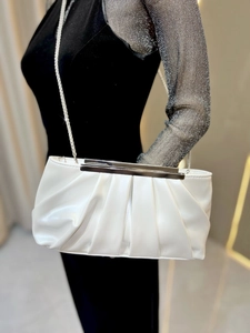 Detail view of white pleated evening clutch with silver chain strap and shiny patent finish