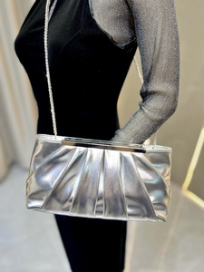Close-up of pleated silver evening clutch with metallic sheen and elegant chain strap