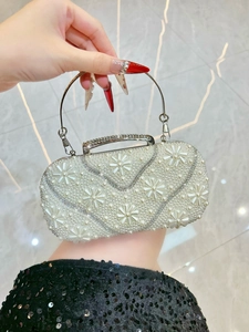 Detail of floral pearl evening clutch with shimmering rhinestone handle and silver frame