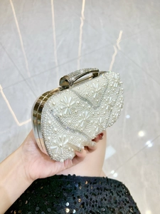 Detail of luxury evening clutch with faux pearls and rhinestones held by a model