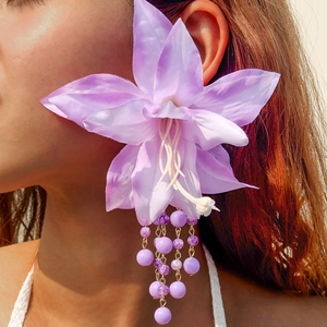 Detailed close-up of oversized purple fabric flower earrings with beaded tassel fringe