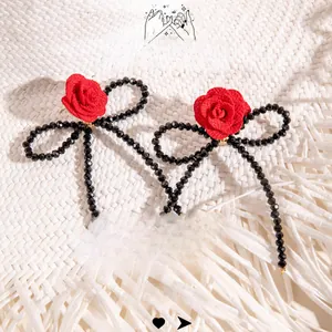 Vue macro de boucles d'oreilles nœuds en perles noires avec roses en tissu rouge 3D