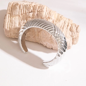 Détail du bracelet jonc argenté avec texture spirale ondulée sur un support en pierre