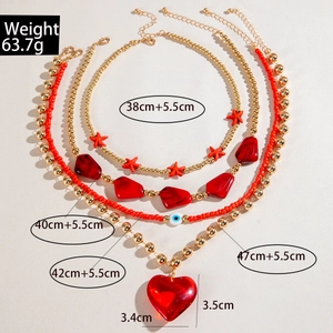 Detail of layered gold necklaces with red heart pendant and evil eye bead details