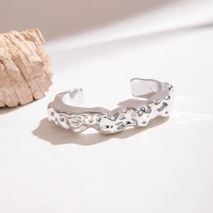 Gros plan sur la texture de lave sur le bracelet jonc ouvert argenté au fini métallique