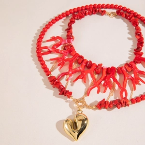 Detail of red branch beads and gold mirror heart pendant on an irregular gravel necklace