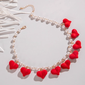 Detail of red flocked heart pendants on a faux pearl necklace with gold-plated lobster clasp