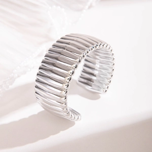 Gros plan d'un bracelet ouvert argenté avec texture ondulée verticale de style luxueux