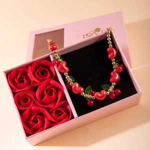 Close-up of red heart pendant necklace in a pink gift box with red roses and gold beads