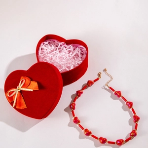 Close-up of red heart acrylic necklace with matching velvet gift box and orange ribbon