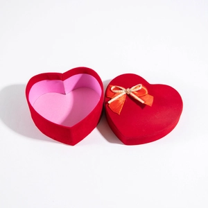 Macro detail of red velvet heart-shaped gift box with a red and gold ribbon bow for jewelry