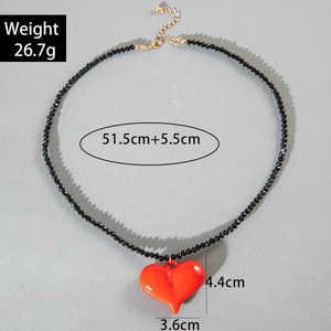 Macro detail of red acrylic heart necklace with size specs and black beaded chain