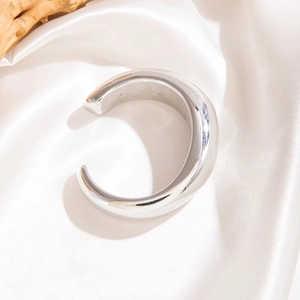 Gros plan détaillé d'un large bracelet jonc argenté en C avec finition polie