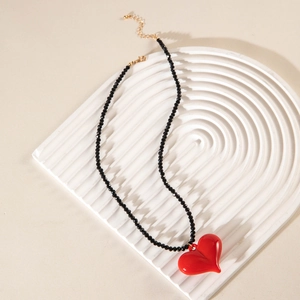 Detail of red acrylic heart pendant on black beaded necklace with gold lobster clasp