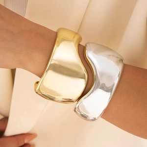 Gros plan de bracelets larges irréguliers or et argent avec finition miroir polie