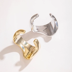 Gros plan de bracelets manchettes ondulés en or et argent avec finition miroir polie