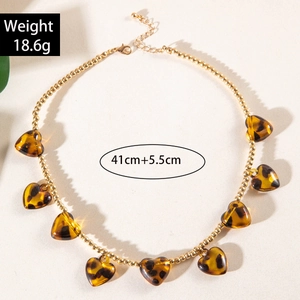 Close-up of leopard print heart pendants on a gold beaded necklace showing size details