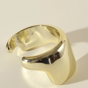Gros plan sur un large bracelet manchette doré poli avec finition miroir et design ouvert