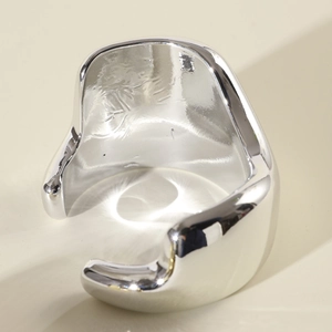 Gros plan sur un bracelet manchette ouvert argenté style métal liquide au fini miroir