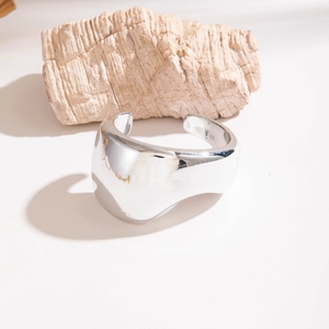 Détail d'un bracelet manchette argenté poli avec des bords ondulés et texture métallique