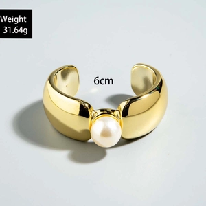 Bracelet manchette doré large avec incrustation de perle blanche centrale détaillé