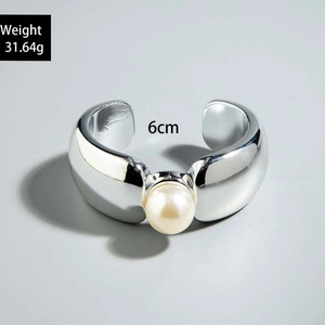 Détail d'un bracelet jonc ouvert argenté épais avec une grande perle centrale