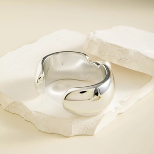 Détail d'un bracelet manchette ouvert argenté avec une finition miroir fluide
