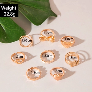 8-piece gold-tone fashion ring set with heart and bow designs on grey background