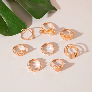 8-piece gold fashion ring set featuring heart and bow designs on a beige background
