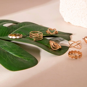Detail of 7-piece gold-tone fashion ring set featuring heart and enamel accents on leaves