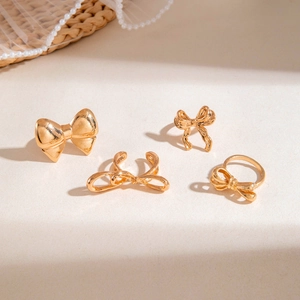 Detailed view of a gold-plated bow ring set featuring heart and knot designs