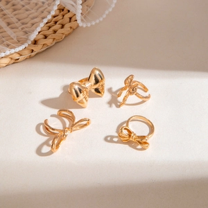 Detail shot of a 4-piece gold bow ring set on a warm textured aesthetic background