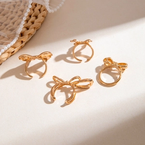 Close-up of gold bow rings stacked on textured background with elegant pearl lace