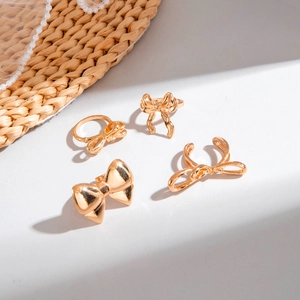 Detail view of gold-plated bow rings and jewelry set on pearl lace and woven mat