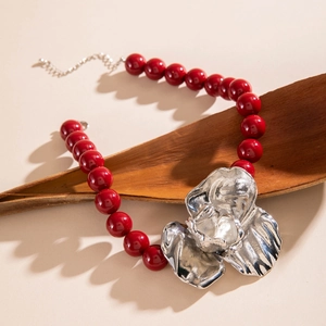 Detail of chunky burgundy resin beads with a metallic silver flower pendant and texture